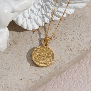 Close-up of golden coin pendant featuring Dos Pesos engraving on vintage bead chain