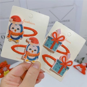 Close-up of cute Christmas hair clips with penguin and gift box designs on cards