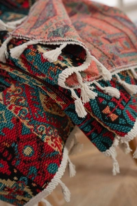 Close-up of geometric jacquard curtain fabric featuring colorful patterns and white cotton tassels