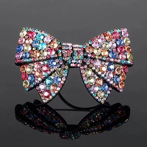 Bow hair clip with colorful rhinestones on a reflective dark surface