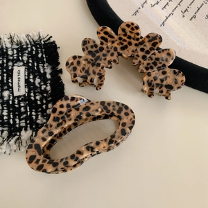 Set of two leopard print acetate hair claws in cloud and oval shapes on tweed fabric
