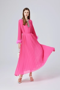 Détail d'une robe plissée fuchsia avec décolleté perlé et poignets en plumes