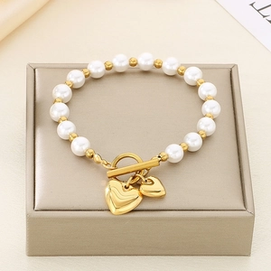 Detail of gold pearl bracelet featuring heart pendants and OT toggle clasp on silk