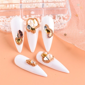 Detail of white pointed nails with gold chains and elegant pearl embellishments