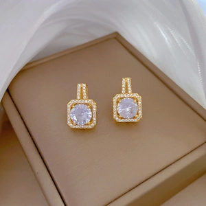 Macro detail of gold square halo earrings with cubic zirconia on brown leather box