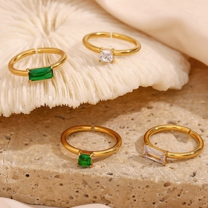 Artistic close-up of 18K gold plated Y2K rings with green and white cubic zirconia