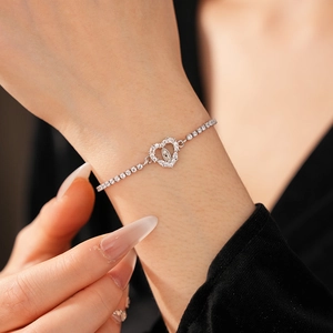 Close-up of a silver tennis bracelet featuring a heart-shaped Virgin Mary charm with zircons