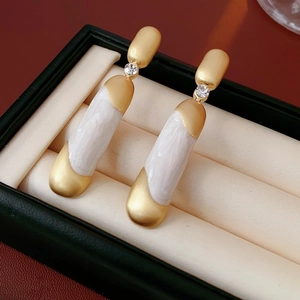 Dettaglio di orecchini vintage dorati con resina marmorizzata bianca e zircone in box