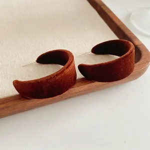 Chic brown velvet flocked C-shaped hoop earrings on a rustic linen display tray