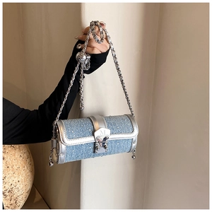 Detail of blue denim cylinder bag with silver chain strap and metal M buckle