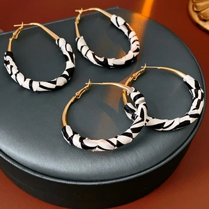 Vue détaillée des boucles d'oreilles zébrées avec des accents dorés et texture cuir torsadé
