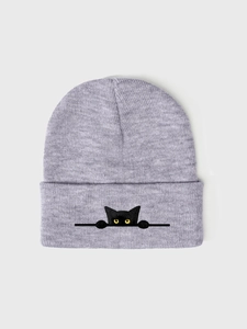 Dettaglio del ricamo a forma di gatto nero su un berretto in maglia grigio chiaro
