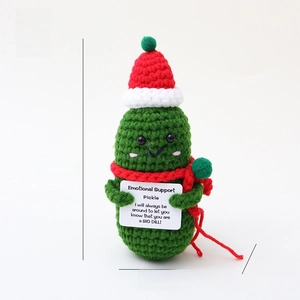 Handmade crochet Christmas pickle doll with red hat and scarf, cute holiday decor detail.