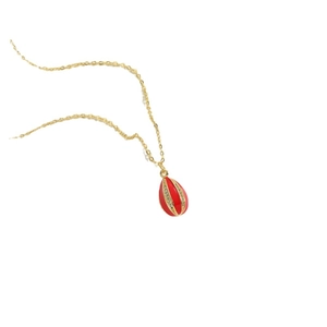 Elegant gold necklace with red egg-shaped pendant and clear zircon accents on white background