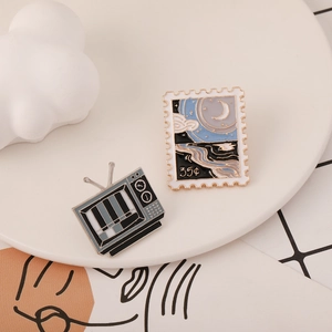 Cartoon enamel pin set with retro TV and scenic stamp designs on a white plate