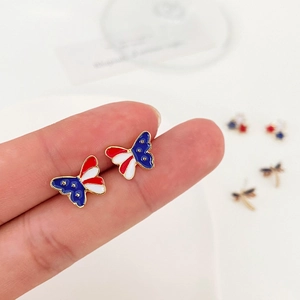 Handheld view of gold plated butterfly earrings with US flag enamel stars and stripes pattern