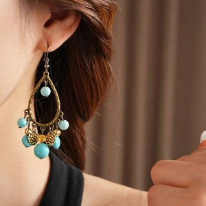Detailed close-up of ethnic style teardrop earrings with blue turquoise and small bells