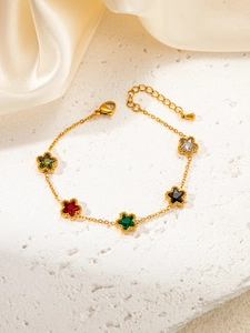 Detailed shot of gold bracelet with five colorful star shaped zircon charms on stone texture