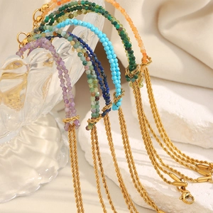 Detail of 18K gold twist chain bracelet with colorful natural stones on stone display