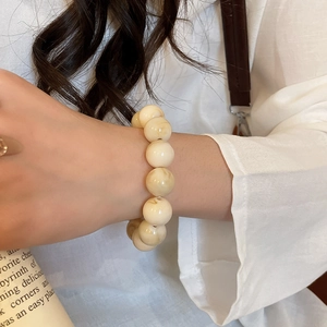 Detail of cream acrylic beaded bracelet with vintage marble texture on a female wrist