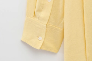 Detailed macro view of pale yellow cotton linen shirt cuff with fine stitching texture