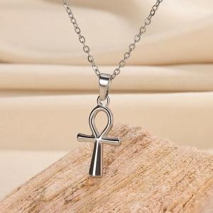 Detailed macro shot of a silver Ankh pendant necklace on a natural wooden background