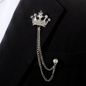 Détail d'une broche couronne argentée avec strass et chaînes pendantes sur un costume