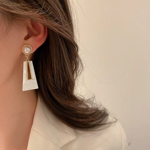 Detail of geometric acrylic earring with gold triangle frame and pearl stud on model