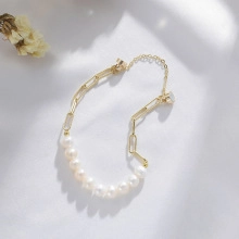 Close-up of golden paperclip chain and freshwater pearl bracelet with adjustable clasp
