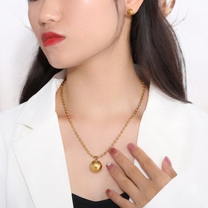 Minimalist golden ball necklace and earrings jewelry set worn by a professional model