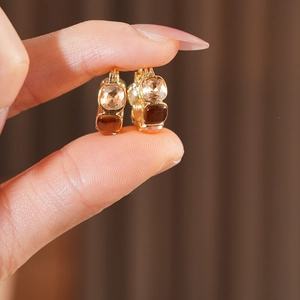 Macro shot of gold metal earrings with champagne and brown square resin stones