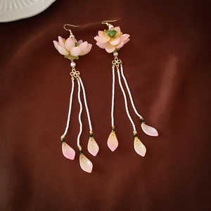 Macro shot of pink lotus petal earrings with white bead tassels and golden hooks