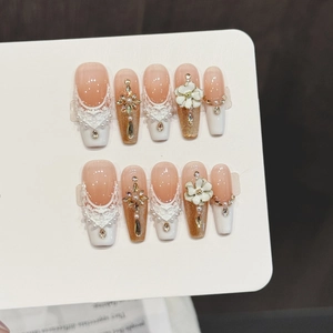 Handmade press-on nails with orange lace, white floral charms and sparkling rhinestones