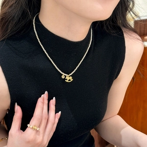 Détail d'un collier de perles avec pendentif cheval et bague dorée assortie sur modèle
