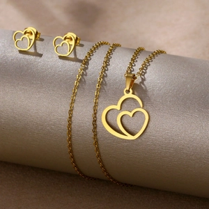 Polished gold heart jewelry set including necklace and earrings on a grey display