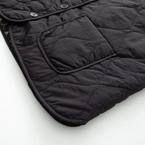 Detail of black quilted vest featuring leopard print lining and buttoned pocket