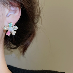 Close-up of elegant flower stud earrings with crystals and pearl on a female ear