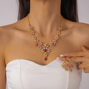 Close-up of gold flower jewelry set with pink stones and sparkling teardrop pendant