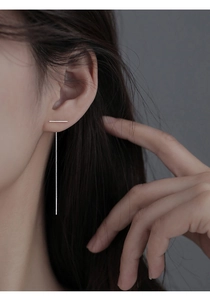 Macro shot of minimalist silver T-shaped ear threader earring on model's ear detail