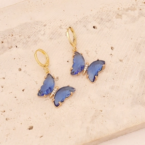 Detail of gold butterfly hoop earrings with blue transparent wings and white crystals
