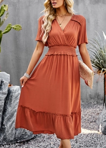 Detail of rust orange V-neck midi dress with elastic waist and ruffle hem outdoors