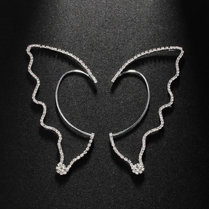 Macro shot of silver butterfly wing ear cuffs with sparkling crystals on black background