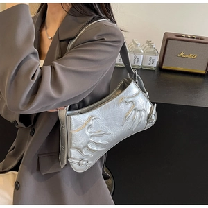 Detail of silver metallic baguette bag featuring flame relief on shoulder of grey blazer