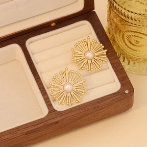 Macro detail of sunburst pearl earrings in a wooden jewelry box with a vintage glass