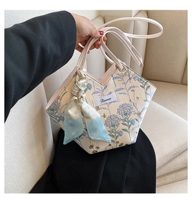 Detail view of the elegant blue floral pattern on the cream canvas tote bag with silk scarf