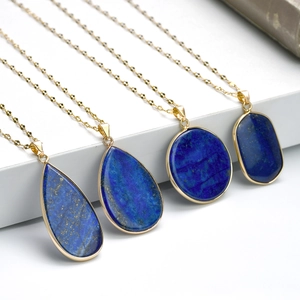 Détail de quatre colliers dorés avec pendentifs en lapis-lazuli sur un support blanc