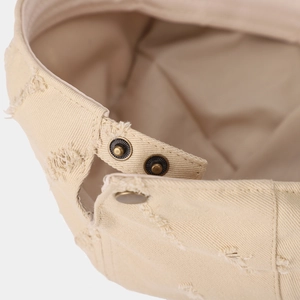 Detail of vintage beige cotton newsboy hat showing retro metal snap buttons and distressed edges