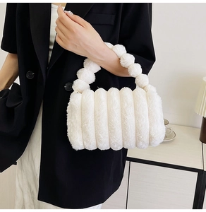 Detail of soft white plush handbag with decorative furry ball handle for autumn and winter