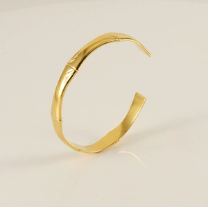 Detailed close-up of a gold bamboo-style stainless steel open cuff bracelet on white