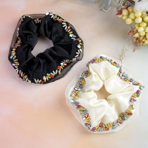 Detail of black and cream satin scrunchies with mesh trim and metallic bead accents